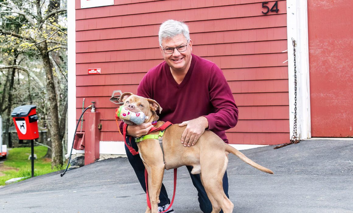 ARL supporter Randy Mason outdoors with a tan pit bull mix dog.