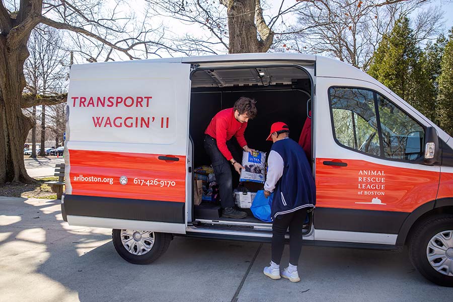 An ARL staff member handing a bag of pet food to someone outside of the ARL Transport Waggin' II