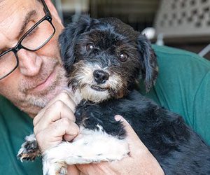 A person holding a small black and white dog